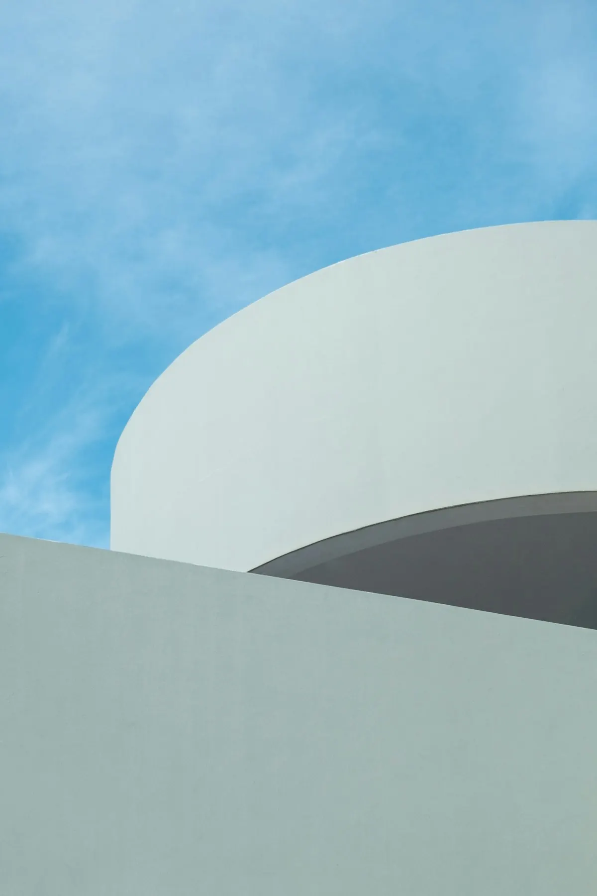 Geschwungene weiße Architektur vor Himmel