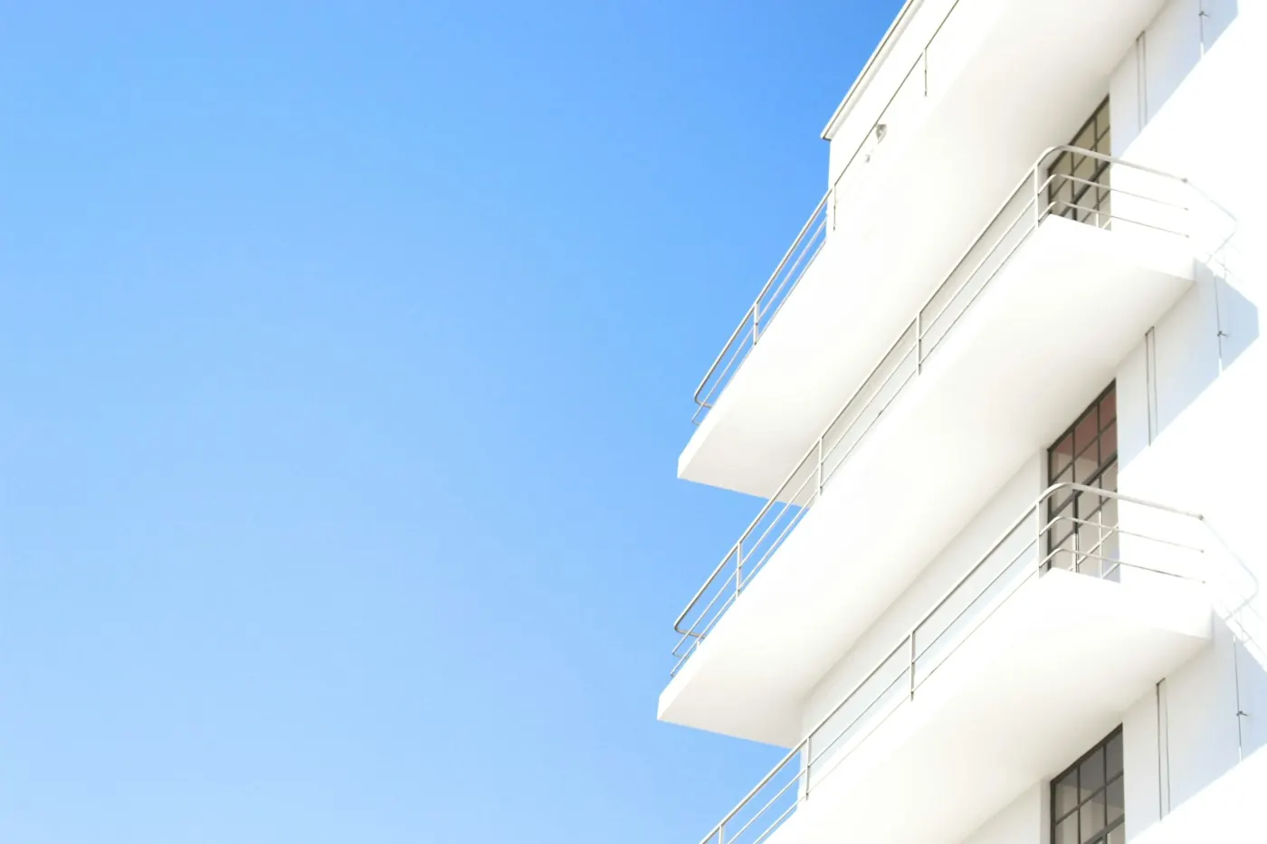 Weiße Balkone eines Wohnhauses vor blauem Himmel